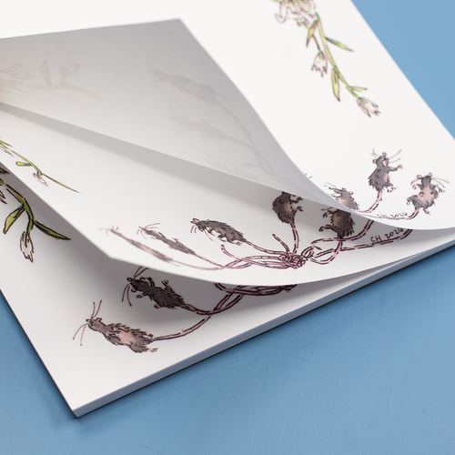 Close up image of the "Rat King Tearaway Notepad" on a blue background. The notepad is being flipped open to show the pages.